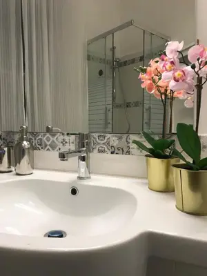 a bathroom sink with a mirror and flowers on it at The Flower Market Apartment in Rome
