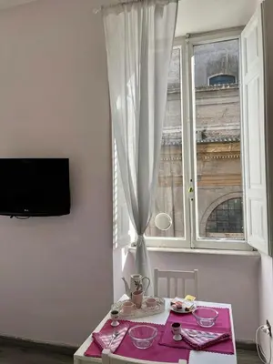 a table in a room with a window and a pink table cloth at ROMA - Loft Campo de' Fiori - Appartamento Campo de' Fiori - LE CUGINE in Rome