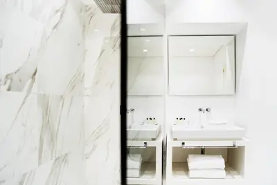 a white bathroom with two sinks and a mirror at The Shire Hotel in Rome
