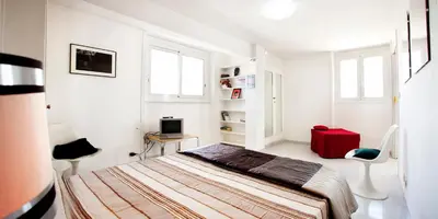 a white bedroom with a bed and a red suitcase at Trastevere Station Terrace in Rome
