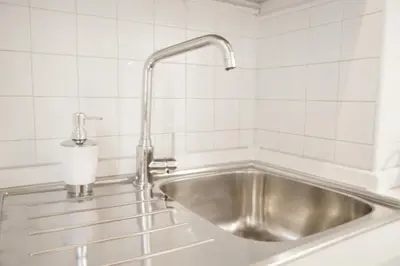 a stainless steel sink in a white tiled kitchen at Paradise Suite Piazza Navona Campo de Fiori in Rome
