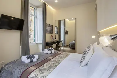 a bedroom with a large bed with a tv on the wall at Quiriti Vatican Relais in Rome