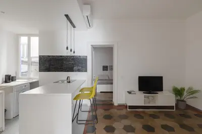 a white kitchen with a counter and a desk with a television at Vicoloft Sales in Rome