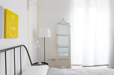 a white bedroom with a bed and a window at Vicoloft Sales in Rome