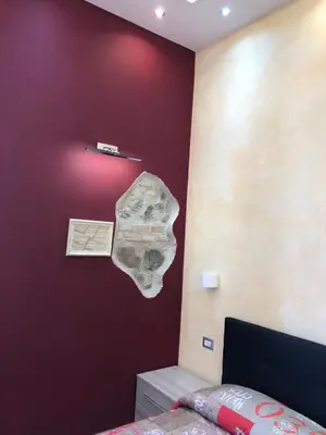 a bedroom with a red wall with a rock on the wall at Vatican Garden in Rome