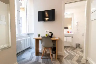 a room with a desk with a chair and a television on the wall at Eccelso Hotel in Rome