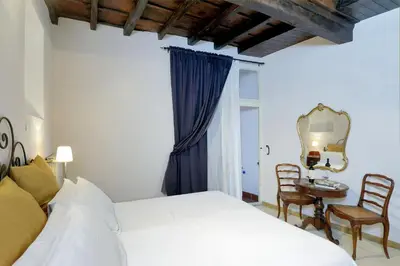 a bedroom with a bed and a table and a mirror at Sangallo Rooms - Residenze Romanae in Rome