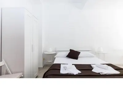 a white bedroom with a bed with two towels on it at Al Colosseo 8 in Rome