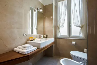 a bathroom with a sink and a toilet and a mirror at Alta Luxury Apartments - Oca Apartment in Rome