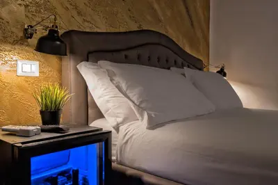 a bed with white pillows and a night stand with a lamp at StarHome Navona in Rome