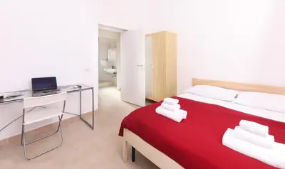 a bedroom with a red bed and a desk with a computer at Cielo Vaticano Guest House in Rome