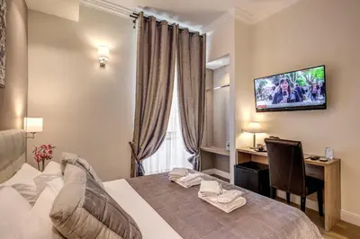 a bedroom with a bed and a desk and a television at Chester Suites in Rome