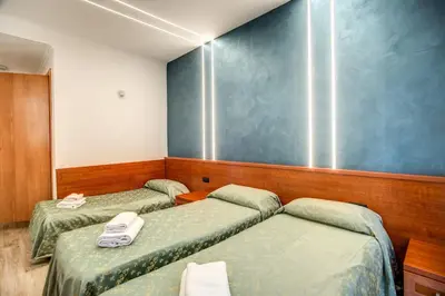 a room with three beds and a blue wall at Hotel Millerose in Rome
