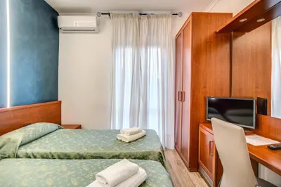 a hotel room with two beds and a desk and a television at Hotel Millerose in Rome