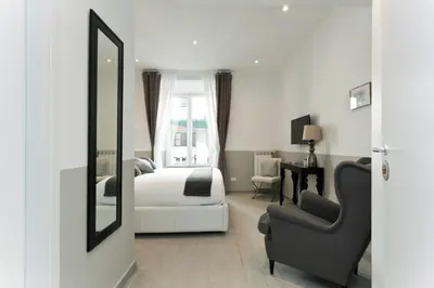 a bedroom with a bed and a chair and a mirror at Aeterna Rooms Collection GuestHouse in Rome