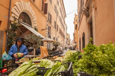 a woman standing at an outdoor vegetable stand in a street at Casa Fabbrini Fancy Suites in Rome