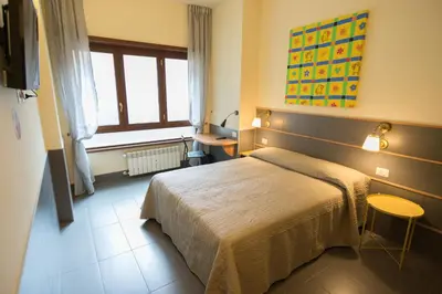 a bedroom with a bed and a desk and a window at tiaspettoaroma in Rome