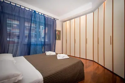 a bedroom with a bed and a window with blue curtains at Elettra Luxury Home in Rome