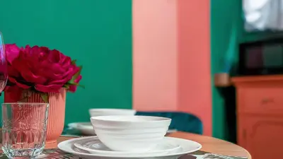 a table with plates and a vase with a red flower at Colosseum Charme Apartments in Rome