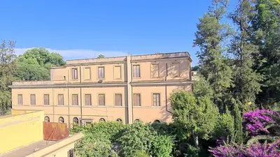 a large building with trees and purple flowers at Villa Riari Garden in Rome
