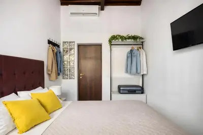a bedroom with a bed with yellow pillows and a television at Urbana 37 Maison - Rione Monti by RHR in Rome