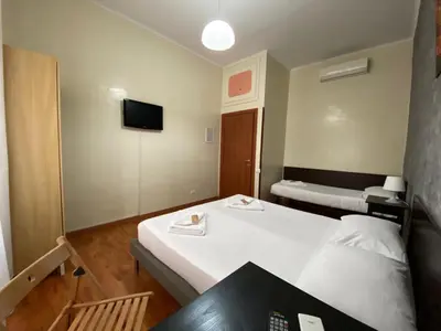 a room with two beds and a table and a tv at The Place In Rome Guest House in Rome