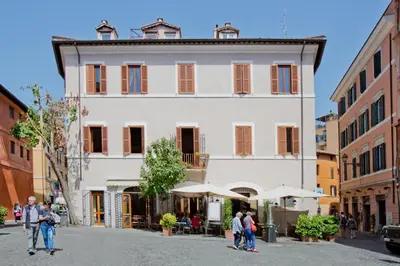 a large white building with people walking in a street at Il Leopardo (Trastevere) in Rome