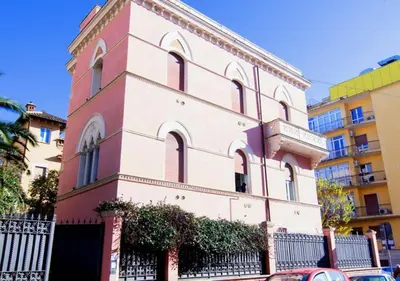 a pink and white building with a fence at Relais Villa Coppedè in Rome