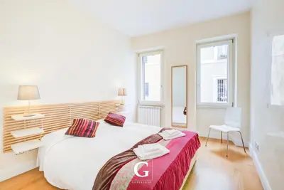 a white bedroom with a large white bed and two windows at Residenza Gonfalone in Rome