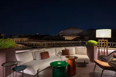 a balcony with a couch and chairs on a roof at The Pantheon Iconic Rome Hotel, Autograph Collection in Rome