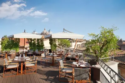 an outdoor patio with tables and chairs and umbrellas at The Pantheon Iconic Rome Hotel, Autograph Collection in Rome