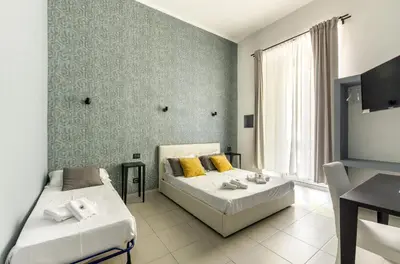 a bedroom with two beds and a table and a television at Merulana 139 Suites in Rome
