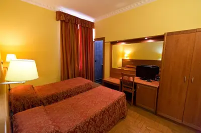 a hotel room with two beds and a desk with a television at Hotel Lella in Rome
