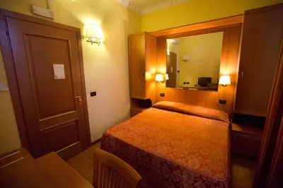 a small room with a bed and a mirror at Hotel Lella in Rome