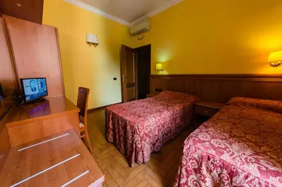 a hotel room with two beds and a desk at Hotel Lella in Rome