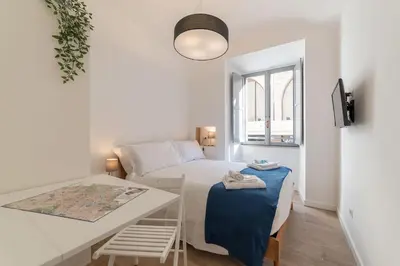 a small white bedroom with a bed and a table at Roma Station House in Rome