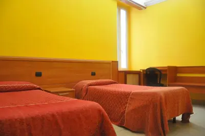 a room with two beds and a yellow wall at Hotel Beauty in Rome