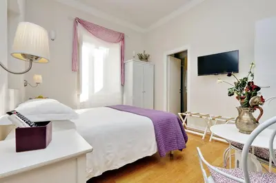 a bedroom with a bed and a table and a tv at Guest House Amaranto Romano in Rome