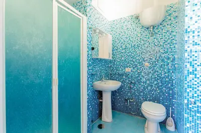 a blue tiled bathroom with a toilet and a sink at Flower guesthouse in Rome