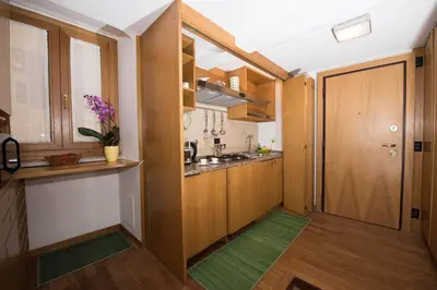 a small kitchen with wooden cabinets and a door at AmoRoma Francesca in Rome