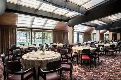 a dining room with tables and chairs and windows at Ergife Palace Hotel in Rome