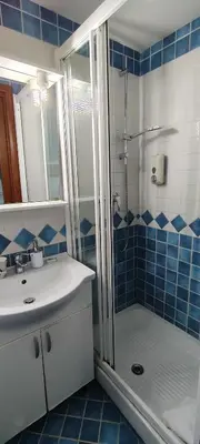a blue tiled bathroom with a shower and a sink at Marco Aurelio in Rome