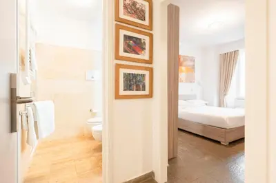 a white bedroom with a bed and a tv on a wall at Manfredi House San Pietro in Rome