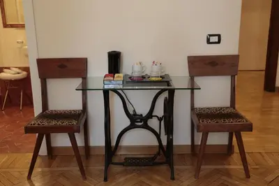 a glass table with two chairs and a table with cups on it at Residenza Delle Arti in Rome