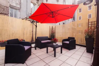 a red umbrella on a patio with chairs and a table at Leonina 75 Holidays in Rome