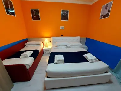 two beds in a room with an orange wall at Hotel Positano in Rome