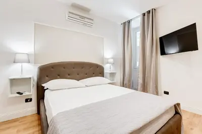 a white bedroom with a bed and a television at Vaticano Private Apartment in Rome
