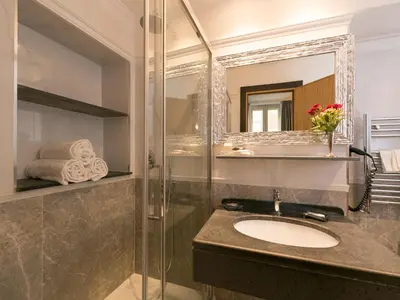 a bathroom with a sink and a shower with a mirror at DK Suites in Rome