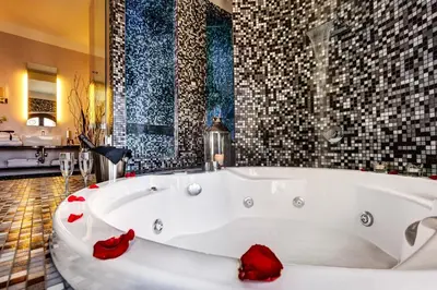 a white bath tub in a bathroom with red roses at Dharma Luxury Hotel & SPA in Rome