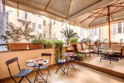 a patio with tables and chairs on a balcony at Little Queen Suite in Rome